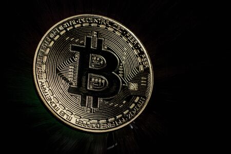 Backlit golden bitcoin coin on black backgroundの写真素材