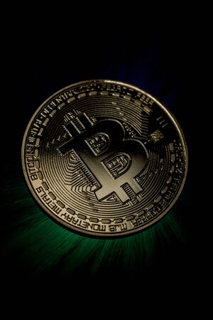 Backlit golden bitcoin coin on black backgroundの写真素材