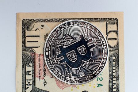 Silver bitcoin on a background of dollarsの写真素材
