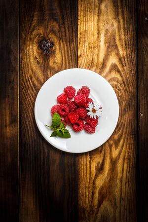 Ripe raspberries and flower on a wooden surfaceの写真素材