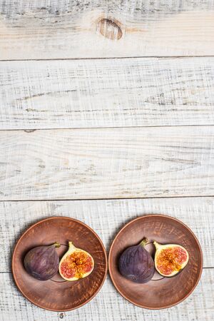 Ripe figs on a plate on a white wooden surfaceの写真素材