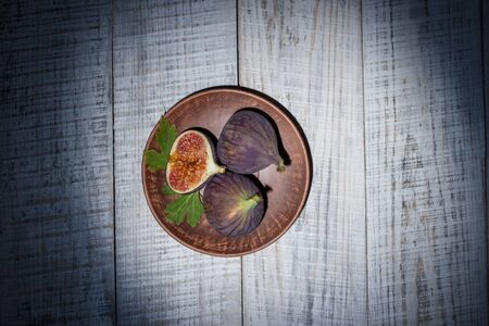 Ripe figs on a plate on a white wooden surfaceの写真素材