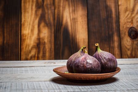 Ripe figs on a plate on a white wooden surfaceの写真素材