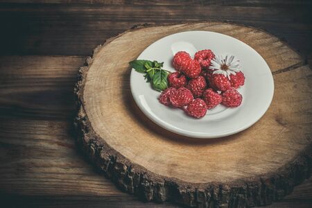 Ripe raspberries and flower on a wooden surfaceの写真素材
