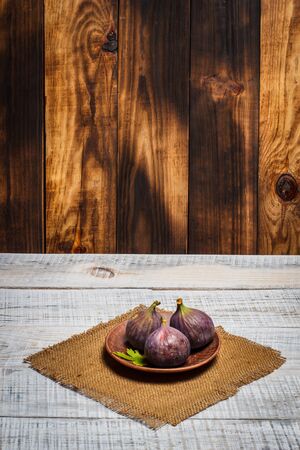 Ripe figs on a plate on a white wooden surfaceの写真素材