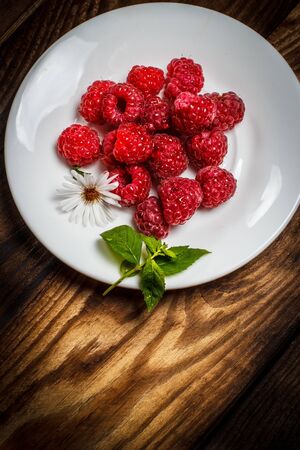 Ripe raspberries and flower on a wooden surfaceの写真素材