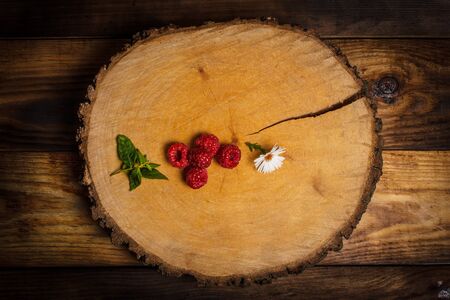 Ripe raspberries and flower on a wooden surfaceの写真素材