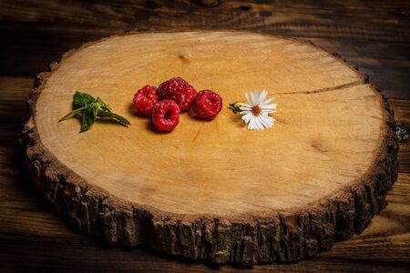 Ripe raspberries and flower on a wooden surfaceの写真素材