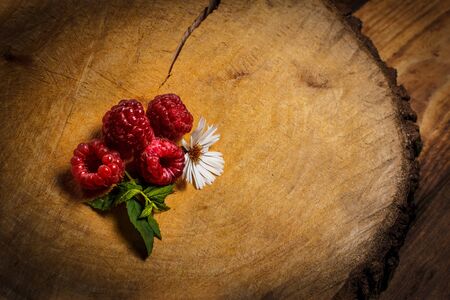 Ripe raspberries and flower on a wooden surfaceの写真素材