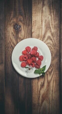 Ripe raspberries and flower on a wooden surfaceの写真素材