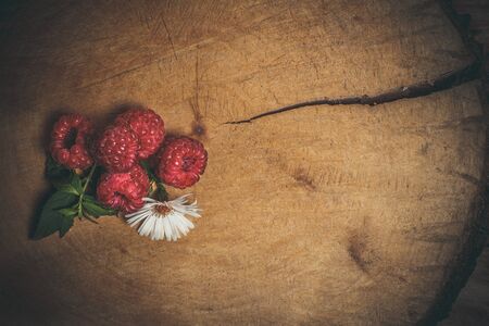 Ripe raspberries and flower on a wooden surfaceの写真素材
