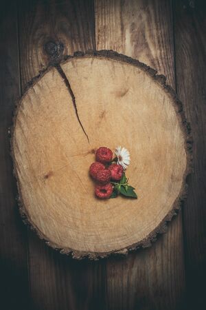 Ripe raspberries and flower on a wooden surfaceの写真素材
