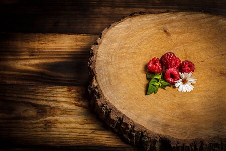 Ripe raspberries and flower on a wooden surfaceの写真素材
