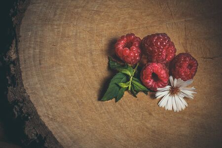 Ripe raspberries and flower on a wooden surfaceの写真素材