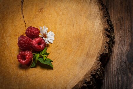 Ripe raspberries and flower on a wooden surfaceの写真素材