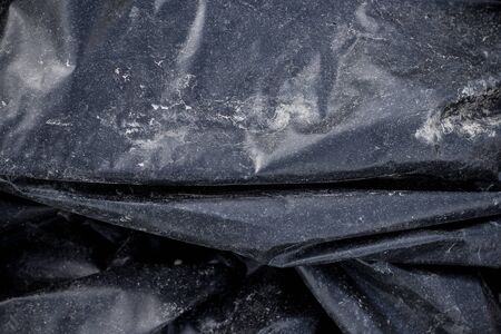 Black plastic crumpled garbage bagの写真素材