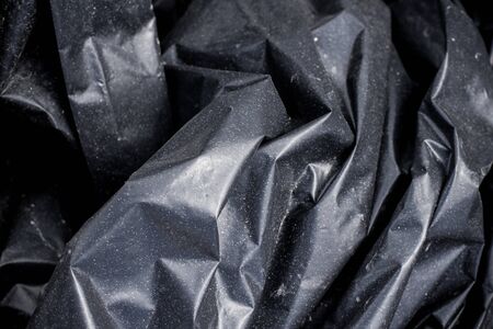 Black plastic crumpled garbage bagの写真素材