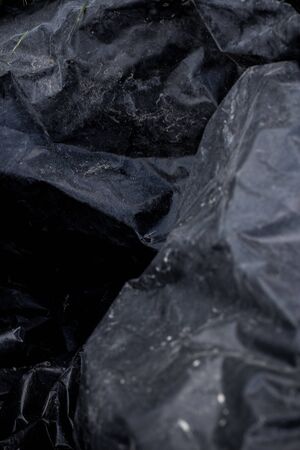 Black plastic crumpled garbage bagの写真素材