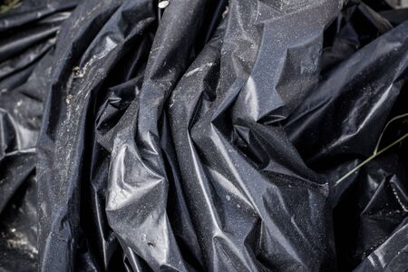 Black plastic crumpled garbage bagの写真素材