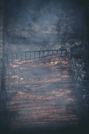 The meat is grilled on a grill with wood and charcoalの写真素材