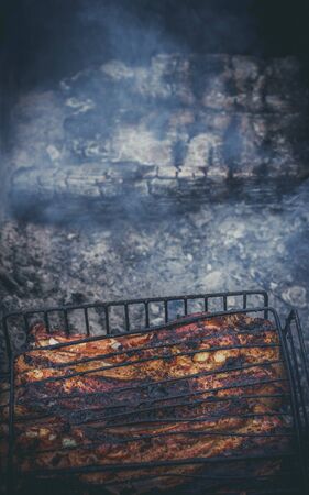 The meat is grilled on a grill with wood and charcoalの写真素材