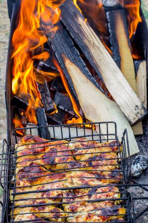 The meat is grilled on a grill with wood and charcoalの写真素材