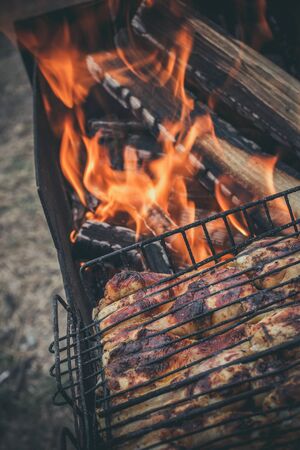 The meat is grilled on a grill with wood and charcoalの写真素材