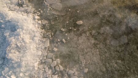 Bid on a frozen river with pieces of ice from a height of flight in the eveningの写真素材