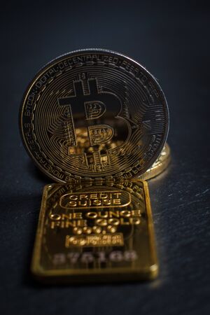 Bitcoins and gold bullion on black background closeの写真素材