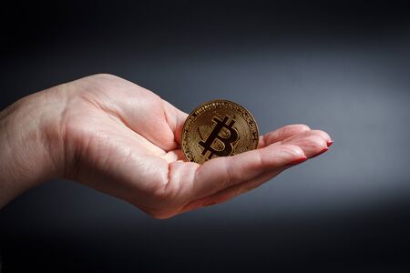 Bitcoins in a girl's hand on a black backgroundの写真素材