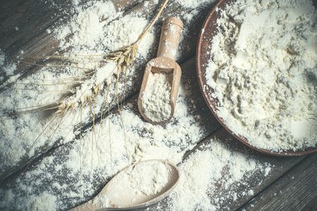 Flour and spikelets of wheat for baking bread lies on a wooden brown surfaceの写真素材
