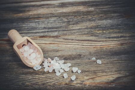 Different spices and salt lie in wooden spoons on a wooden brown tableの写真素材
