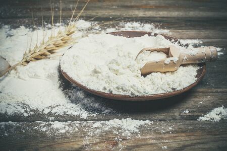 Flour and spikelets of wheat for baking bread lies on a wooden brown surfaceの写真素材