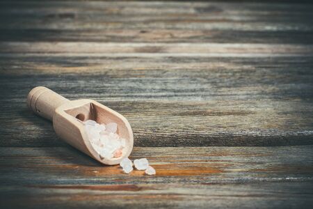 Different spices and salt lie in wooden spoons on a wooden brown tableの写真素材