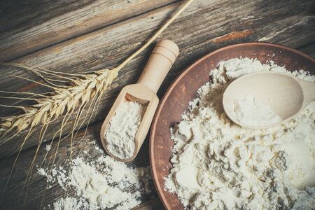 Flour and spikelets of wheat for baking bread lies on a wooden brown surfaceの写真素材