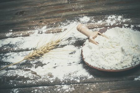 Flour and spikelets of wheat for baking bread lies on a wooden brown surfaceの写真素材