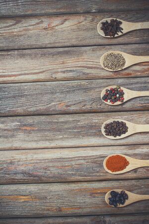 Different spices and salt lie in wooden spoons on a wooden brown tableの写真素材