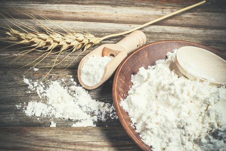 Flour and spikelets of wheat for baking bread lies on a wooden brown surfaceの写真素材
