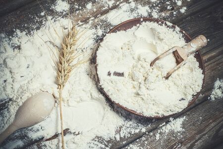 Flour and spikelets of wheat for baking bread lies on a wooden brown surfaceの写真素材