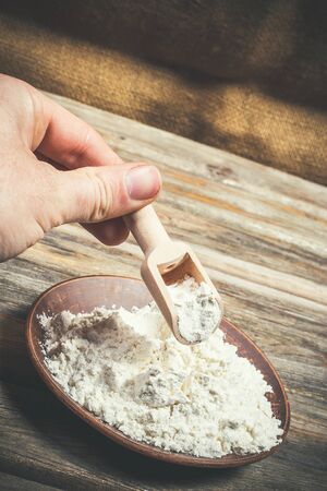 Flour and spikelets of wheat for baking bread lies on a wooden brown surfaceの写真素材