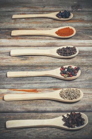 Different spices and salt lie in wooden spoons on a wooden brown tableの写真素材