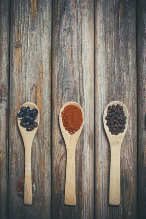 Different spices and salt lie in wooden spoons on a wooden brown tableの写真素材