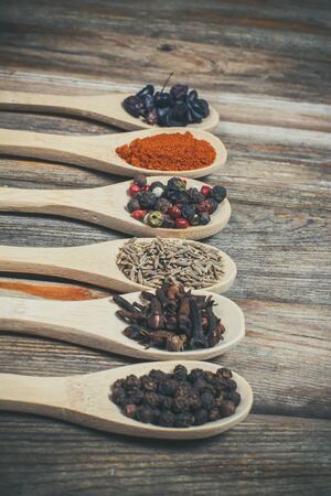 Different spices and salt lie in wooden spoons on a wooden brown tableの写真素材