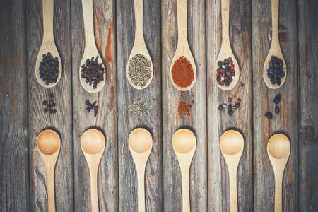Different spices and salt lie in wooden spoons on a wooden brown tableの写真素材