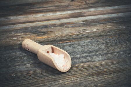Different spices and salt lie in wooden spoons on a wooden brown tableの写真素材
