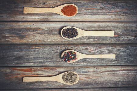 Different spices and salt lie in wooden spoons on a wooden brown tableの写真素材