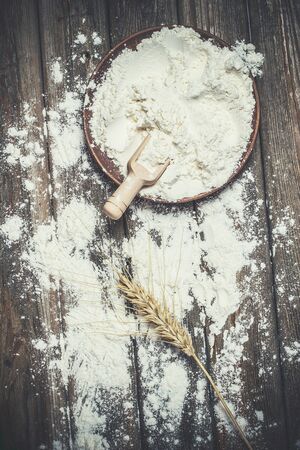 Flour and spikelets of wheat for baking bread lies on a wooden brown surfaceの写真素材