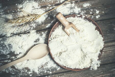 Flour and spikelets of wheat for baking bread lies on a wooden brown surfaceの写真素材