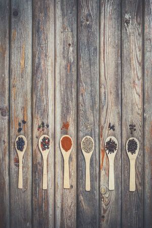 Different spices and salt lie in wooden spoons on a wooden brown tableの写真素材