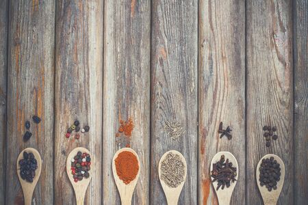 Different spices and salt lie in wooden spoons on a wooden brown tableの写真素材